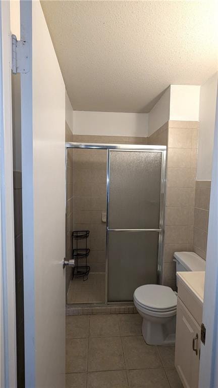 bathroom with tile patterned flooring, vanity, a textured ceiling, and toilet