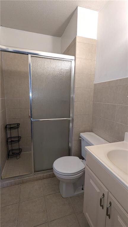 bathroom featuring toilet, an enclosed shower, tile walls, a textured ceiling, and vanity