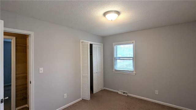 unfurnished bedroom with carpet floors, a closet, and a textured ceiling