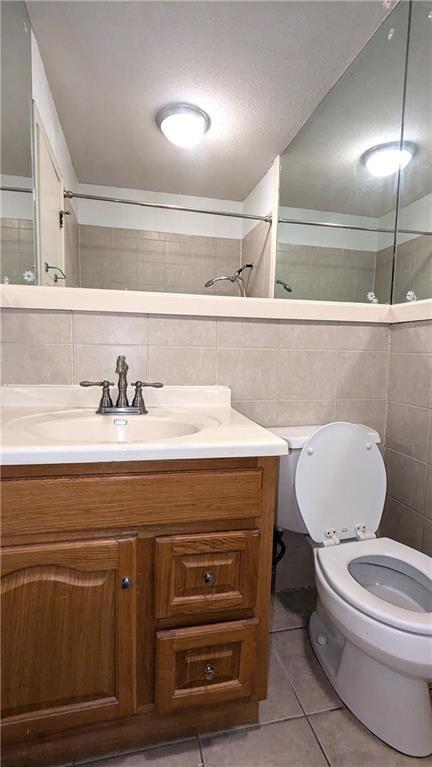 bathroom with vanity, tile patterned floors, tile walls, and toilet