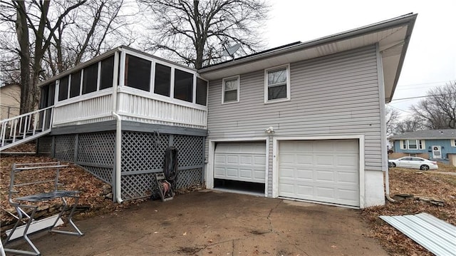 rear view of house featuring a garage and a sunroom