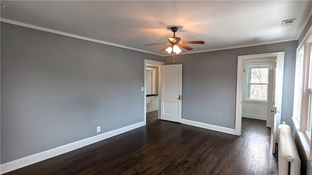 spare room featuring radiator, dark wood-type flooring, ornamental molding, and ceiling fan