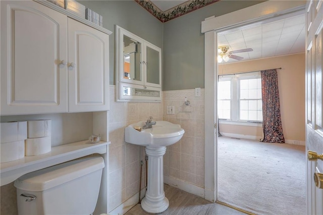 bathroom featuring tile walls, ceiling fan, and toilet