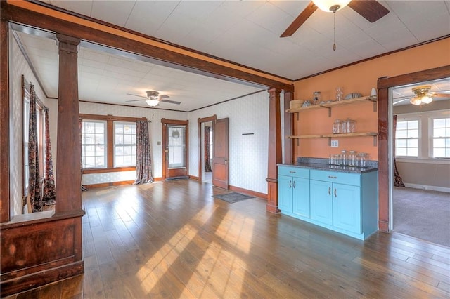 unfurnished living room with crown molding, ceiling fan, hardwood / wood-style floors, and ornate columns