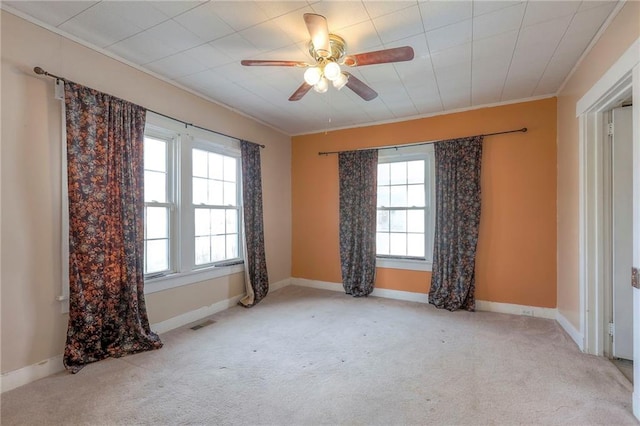 unfurnished room featuring ornamental molding, a wealth of natural light, light colored carpet, and ceiling fan