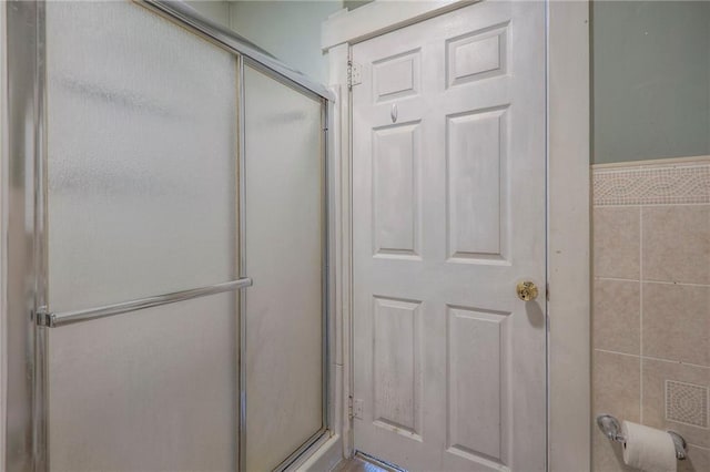 bathroom with tile walls and a shower with shower door