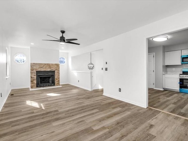 unfurnished living room with ceiling fan, a fireplace, and light hardwood / wood-style floors