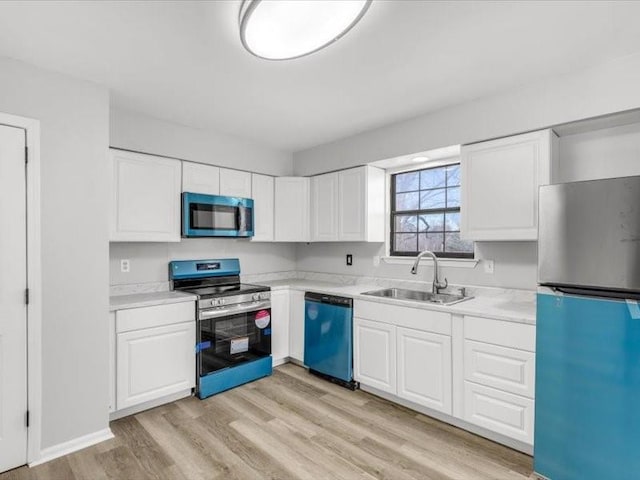 kitchen with stainless steel appliances, white cabinetry, sink, and light wood-type flooring