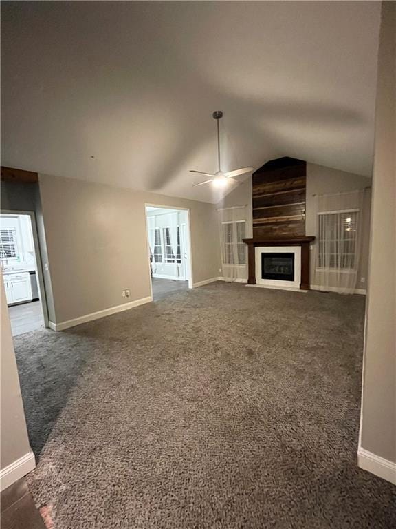 unfurnished living room featuring baseboards, a ceiling fan, lofted ceiling, a fireplace, and dark carpet