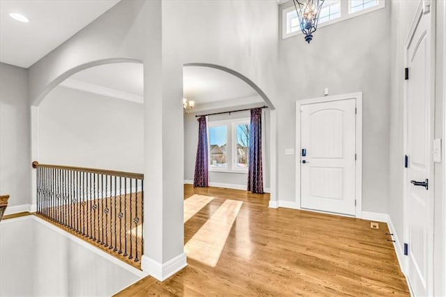 entryway featuring an inviting chandelier, hardwood / wood-style floors, a towering ceiling, and a healthy amount of sunlight