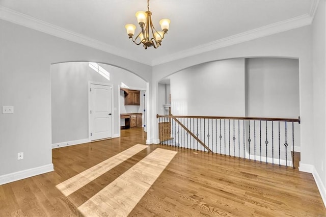 unfurnished room with crown molding, hardwood / wood-style floors, and a notable chandelier