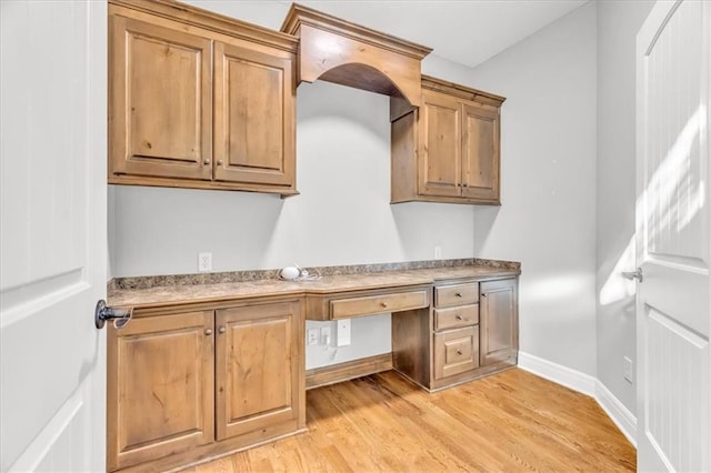 kitchen with built in desk and light hardwood / wood-style floors