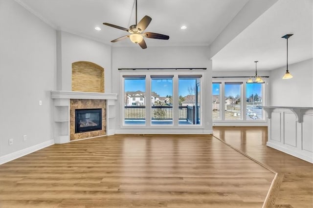 unfurnished living room featuring ceiling fan, a fireplace, and light wood-type flooring