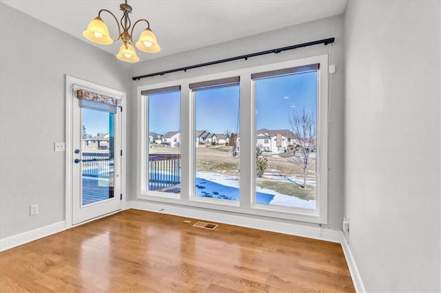 doorway to outside with an inviting chandelier, hardwood / wood-style flooring, and plenty of natural light