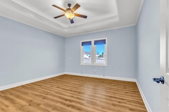 empty room featuring a raised ceiling, crown molding, ceiling fan, and light hardwood / wood-style flooring