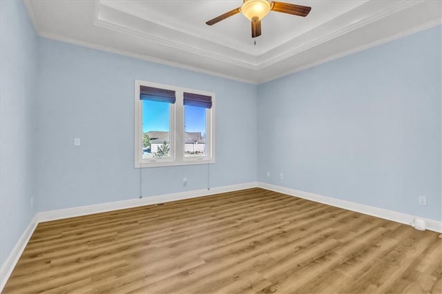 unfurnished room with crown molding, light hardwood / wood-style flooring, a raised ceiling, and ceiling fan