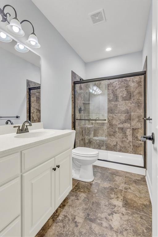 bathroom featuring toilet, vanity, and a shower with shower door