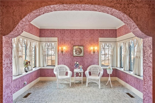 sitting room with wallpapered walls, visible vents, arched walkways, and a textured ceiling