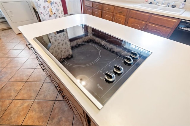 interior details with brown cabinets, light countertops, a sink, washer / dryer, and black electric cooktop