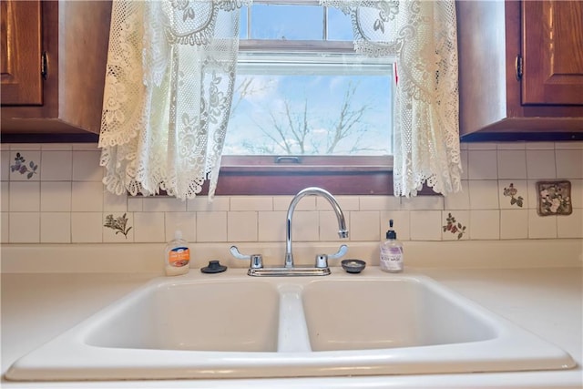 details featuring brown cabinetry, light countertops, a sink, and decorative backsplash