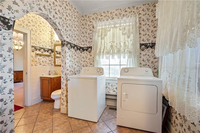 laundry room featuring a wainscoted wall, light tile patterned floors, washer and clothes dryer, and wallpapered walls