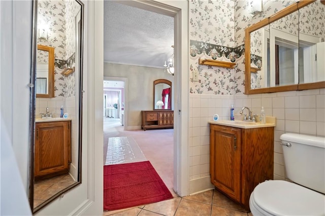 bathroom with vanity, ornamental molding, a textured ceiling, tile patterned floors, and toilet