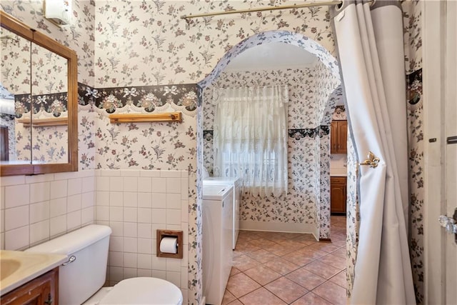 full bath featuring toilet, wallpapered walls, tile patterned floors, and wainscoting