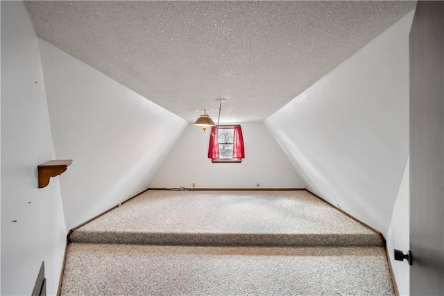 additional living space featuring a textured ceiling, vaulted ceiling, carpet flooring, and baseboards