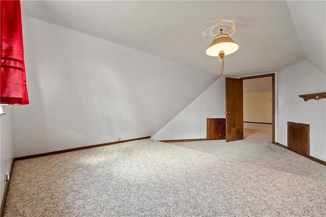 bonus room with carpet floors, vaulted ceiling, and a textured ceiling