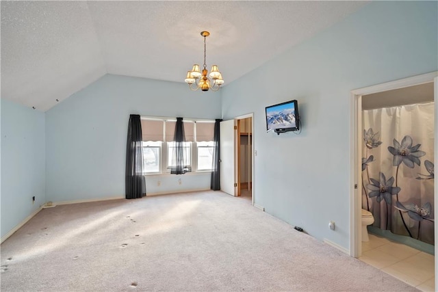 carpeted empty room featuring a chandelier, vaulted ceiling, and a textured ceiling