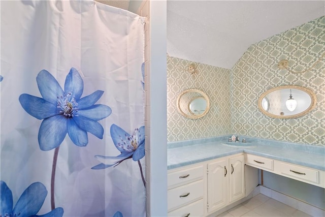 bathroom with lofted ceiling, tile patterned floors, vanity, and wallpapered walls