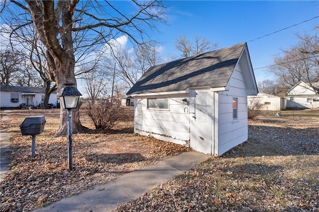 view of property exterior with an outbuilding and a shingled roof