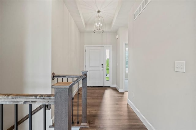 entryway with an inviting chandelier, dark hardwood / wood-style floors, and a raised ceiling