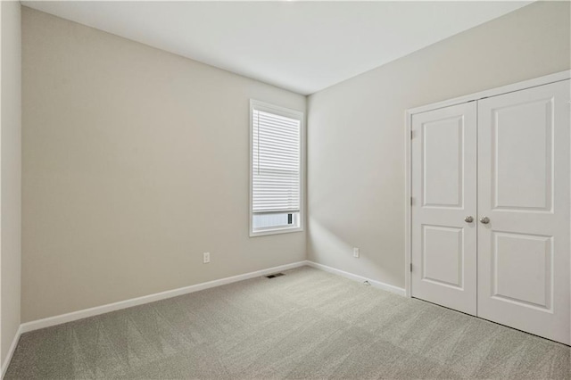 unfurnished bedroom with light colored carpet and a closet