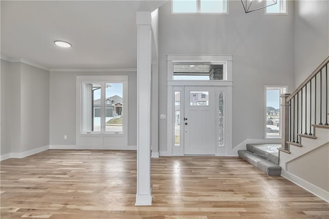 entrance foyer featuring stairs, light wood finished floors, ornamental molding, and baseboards