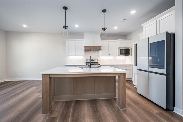 kitchen with a kitchen island with sink, hanging light fixtures, white cabinets, and appliances with stainless steel finishes