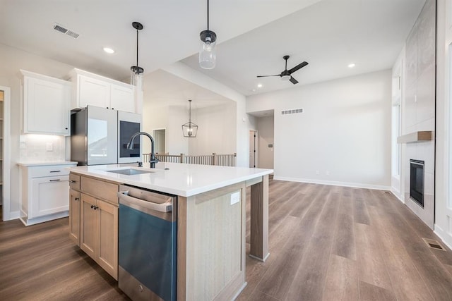 kitchen with pendant lighting, an island with sink, sink, white cabinets, and stainless steel appliances