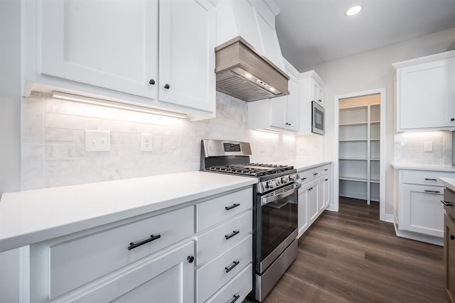 kitchen featuring dark wood-type flooring, premium range hood, white cabinetry, stainless steel appliances, and tasteful backsplash