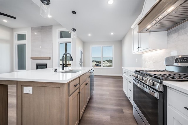 kitchen featuring custom exhaust hood, an island with sink, white cabinets, and appliances with stainless steel finishes