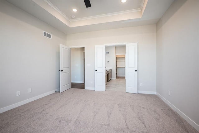 unfurnished bedroom with a raised ceiling, crown molding, light carpet, and ceiling fan