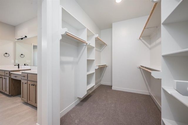 spacious closet with light colored carpet and sink