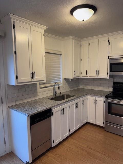 kitchen with sink, light hardwood / wood-style flooring, stainless steel appliances, and white cabinets