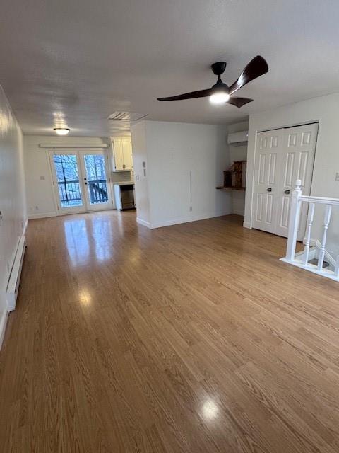 unfurnished living room with ceiling fan, a wall mounted air conditioner, light hardwood / wood-style floors, and a baseboard heating unit