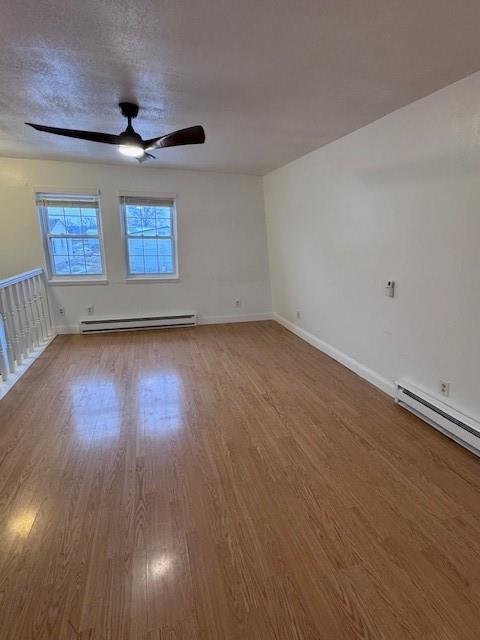 spare room with baseboard heating, ceiling fan, and hardwood / wood-style floors