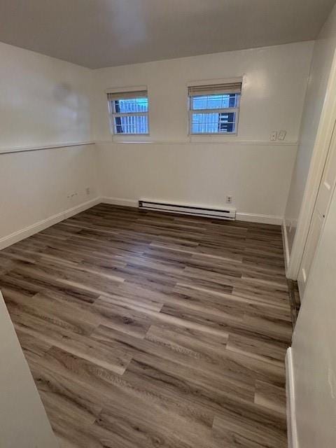 unfurnished room featuring a baseboard radiator, dark hardwood / wood-style floors, and a healthy amount of sunlight