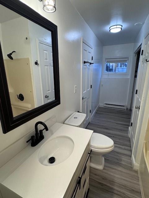 bathroom featuring vanity, a baseboard heating unit, wood-type flooring, and toilet