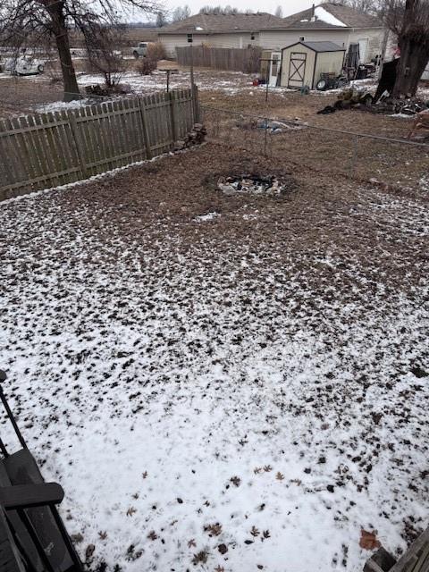 snowy yard featuring a storage unit