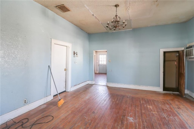 unfurnished room featuring an inviting chandelier and dark hardwood / wood-style floors