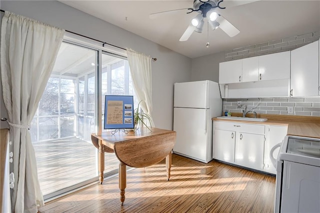 kitchen featuring white cabinetry, sink, ceiling fan, white appliances, and light hardwood / wood-style flooring