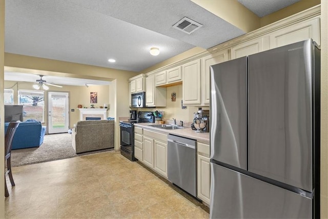 kitchen featuring visible vents, appliances with stainless steel finishes, light countertops, a fireplace, and a sink